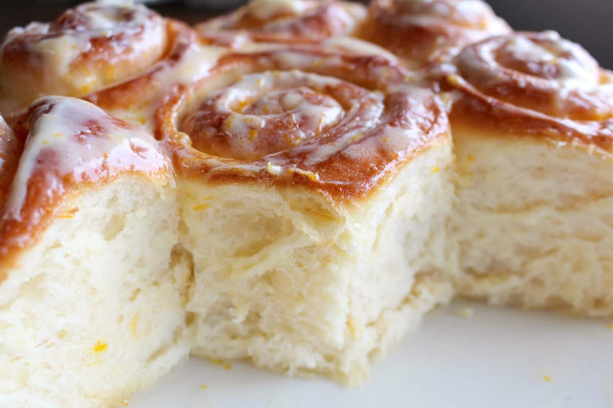 45 degree angle shot of fluffy iced lemon rolls.