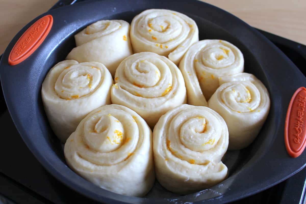Lemon rolls doubled in size in a dark round pan.