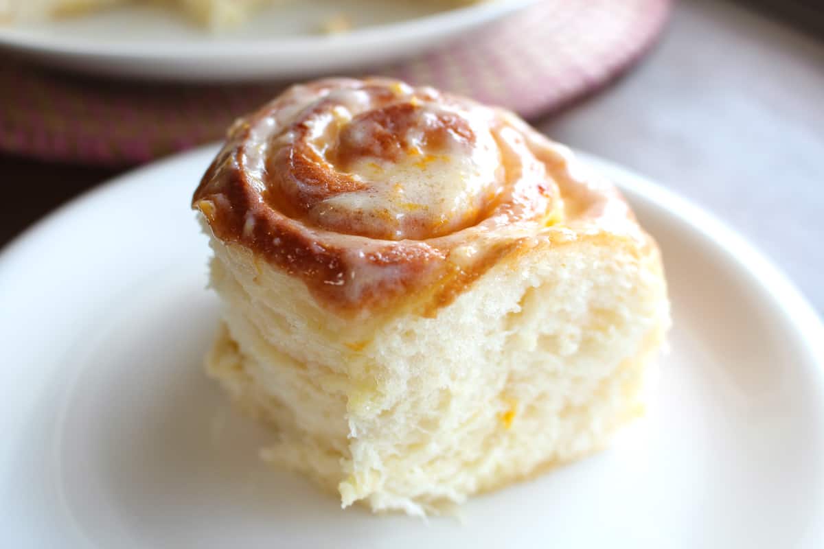 45 degree angle shot of a fluffy lemon roll on a white plate.