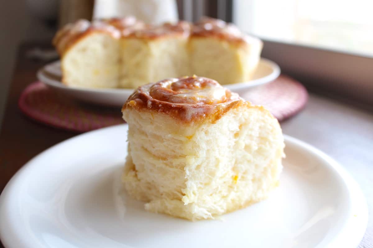 A straight on shot of a fluffy lemon sweet roll on a plate.