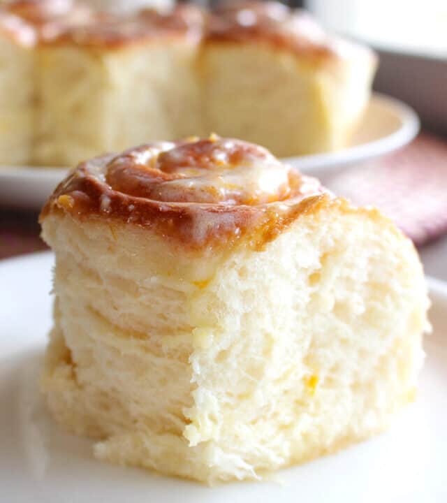A straight on shot of a fluffy lemon sweet roll on a plate.