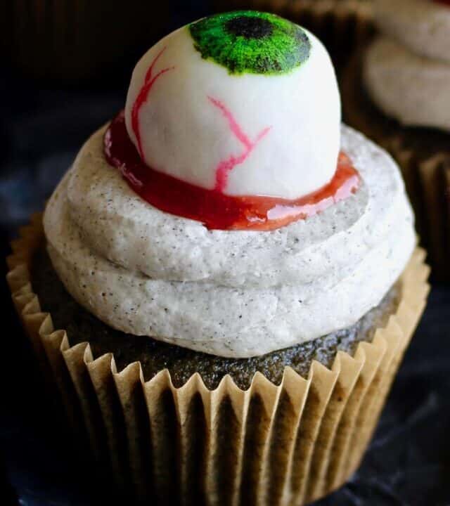 Halloween black sesame cupcakes are the perfect unique treat for an adult Halloween party! These Halloween eyeball cupcakes have a fluffy black sesame cake topped with black sesame buttercream frosting, topped with my Halloween white chocolate eyeballs! I added a spoonful of berry jam as fake blood, but I think mixing some black tahini with honey to make a spooky black goop would pair better in terms of taste. #halloween #halloweentreats #trickortreat #cupcake #cupcakes #blacksesame #kurogoma #sesame #cake #fluffy #black #spooky #creepy #dessert #halloweenparty #adult #eyeballs #whitechocolate #buttercream #frosting