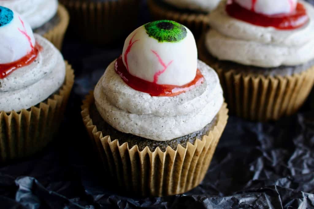 Halloween black sesame cupcakes are the perfect unique treat for an adult Halloween party! These Halloween eyeball cupcakes have a fluffy black sesame cake topped with black sesame buttercream frosting, topped with my Halloween white chocolate eyeballs! I added a spoonful of berry jam as fake blood, but I think mixing some black tahini with honey to make a spooky black goop would pair better in terms of taste. #halloween #halloweentreats #trickortreat #cupcake #cupcakes #blacksesame #kurogoma #sesame #cake #fluffy #black #spooky #creepy #dessert #halloweenparty #adult #eyeballs #whitechocolate #buttercream #frosting
