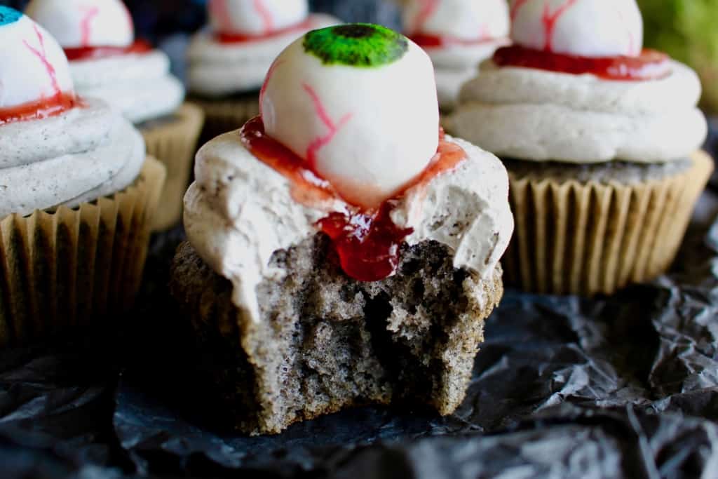 Halloween black sesame cupcakes are the perfect unique treat for an adult Halloween party! These Halloween eyeball cupcakes have a fluffy black sesame cake topped with black sesame buttercream frosting, topped with my Halloween white chocolate eyeballs! I added a spoonful of berry jam as fake blood, but I think mixing some black tahini with honey to make a spooky black goop would pair better in terms of taste. #halloween #halloweentreats #trickortreat #cupcake #cupcakes #blacksesame #kurogoma #sesame #cake #fluffy #black #spooky #creepy #dessert #halloweenparty #adult #eyeballs #whitechocolate #buttercream #frosting