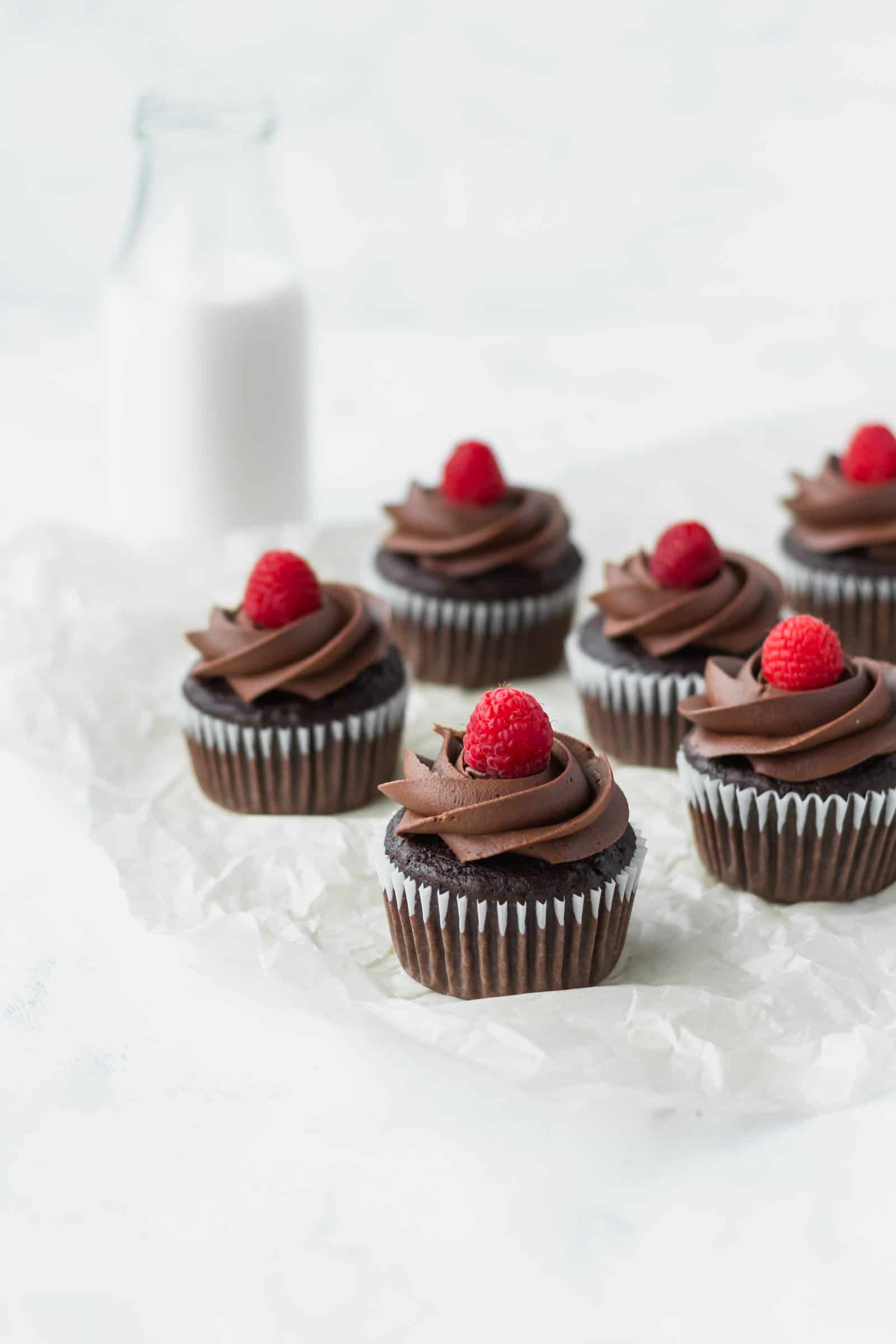 These vegan chocolate banana cupcakes are delicious and moist! Topped with creamy vegan chocolate buttercream and fresh raspberries! #chocolatecupcakes #bananacupcakes #valentinesdaydessert #veganvalentinesday #vegancupcakes