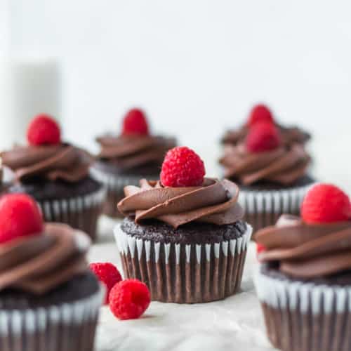 These vegan chocolate banana cupcakes are delicious and moist! Topped with creamy vegan chocolate buttercream and fresh raspberries! #chocolatecupcakes #bananacupcakes #valentinesdaydessert #veganvalentinesday #vegancupcakes