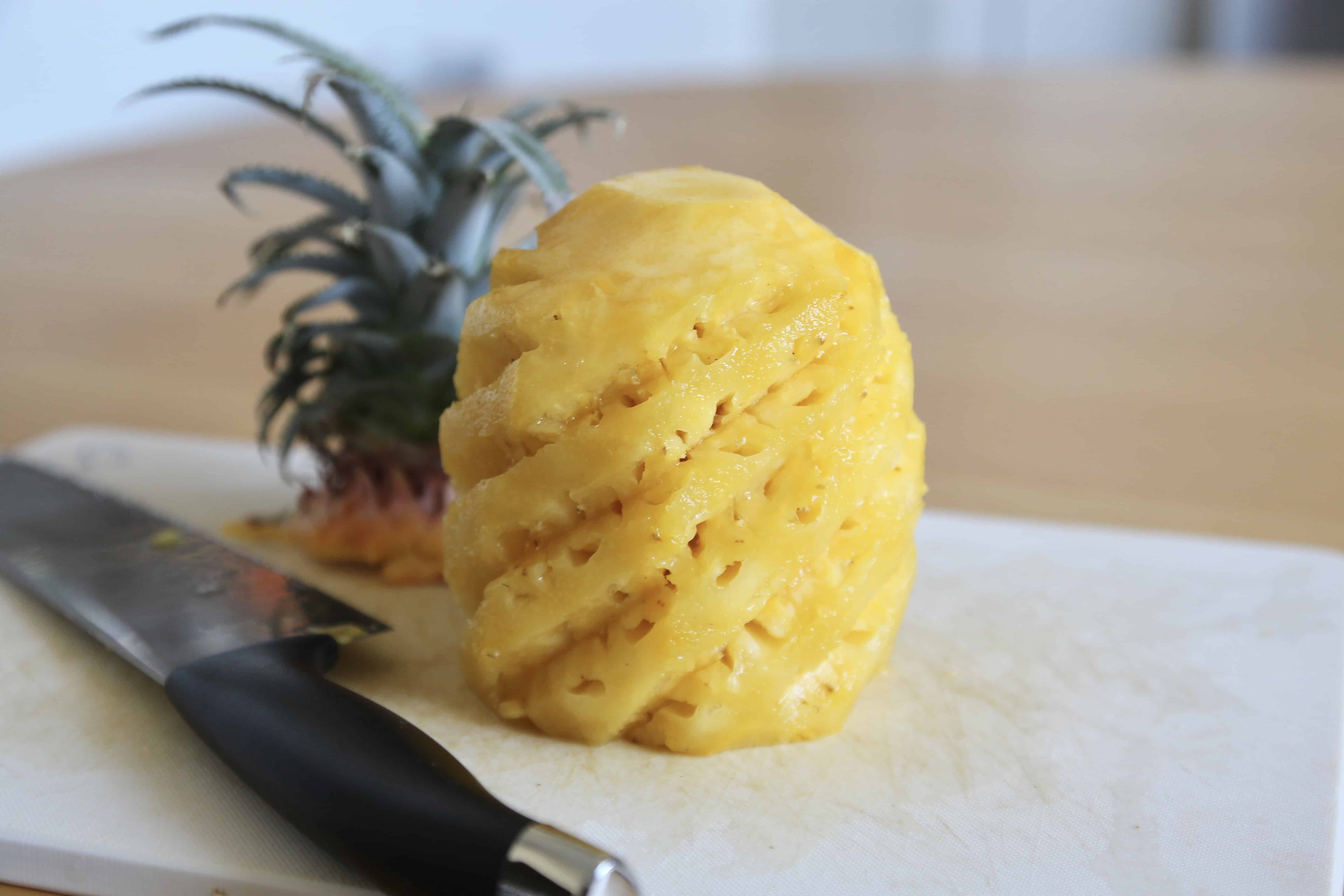 A peeled pineapple with a knife