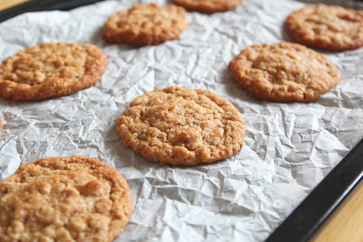 Baked oatmeal cookies on a parchment paper lined baking sheet.