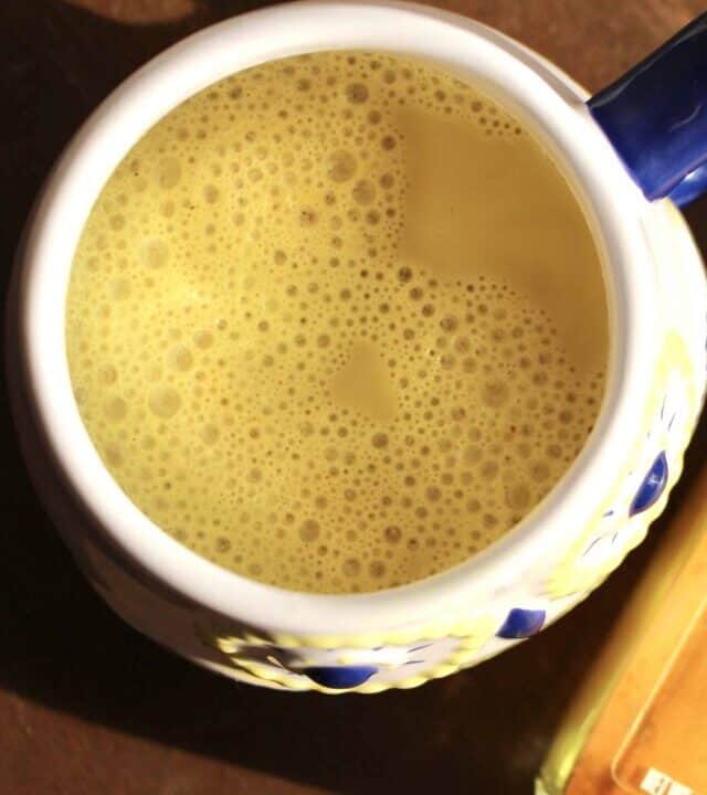 Golden Milk in a mug next to a jar of ground turmeric.