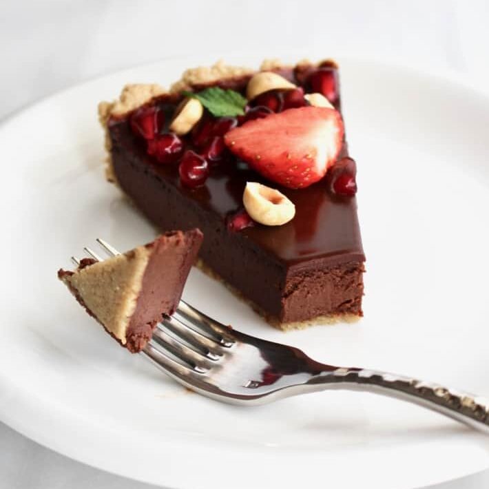 a slice of chocolate bailey's tart on a white plate.