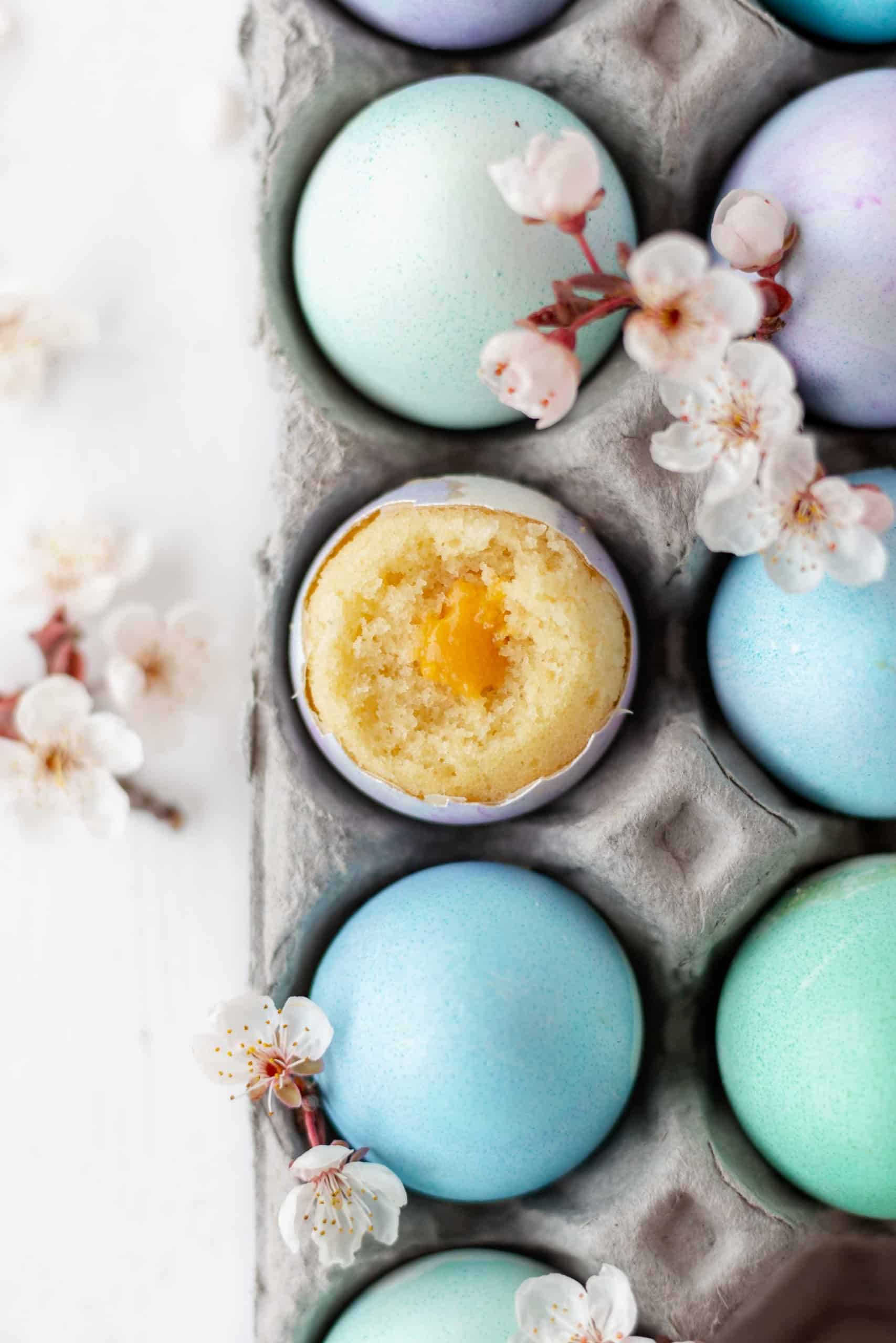 Dyed eggs in a carton with vanilla cake baked in an eggshell