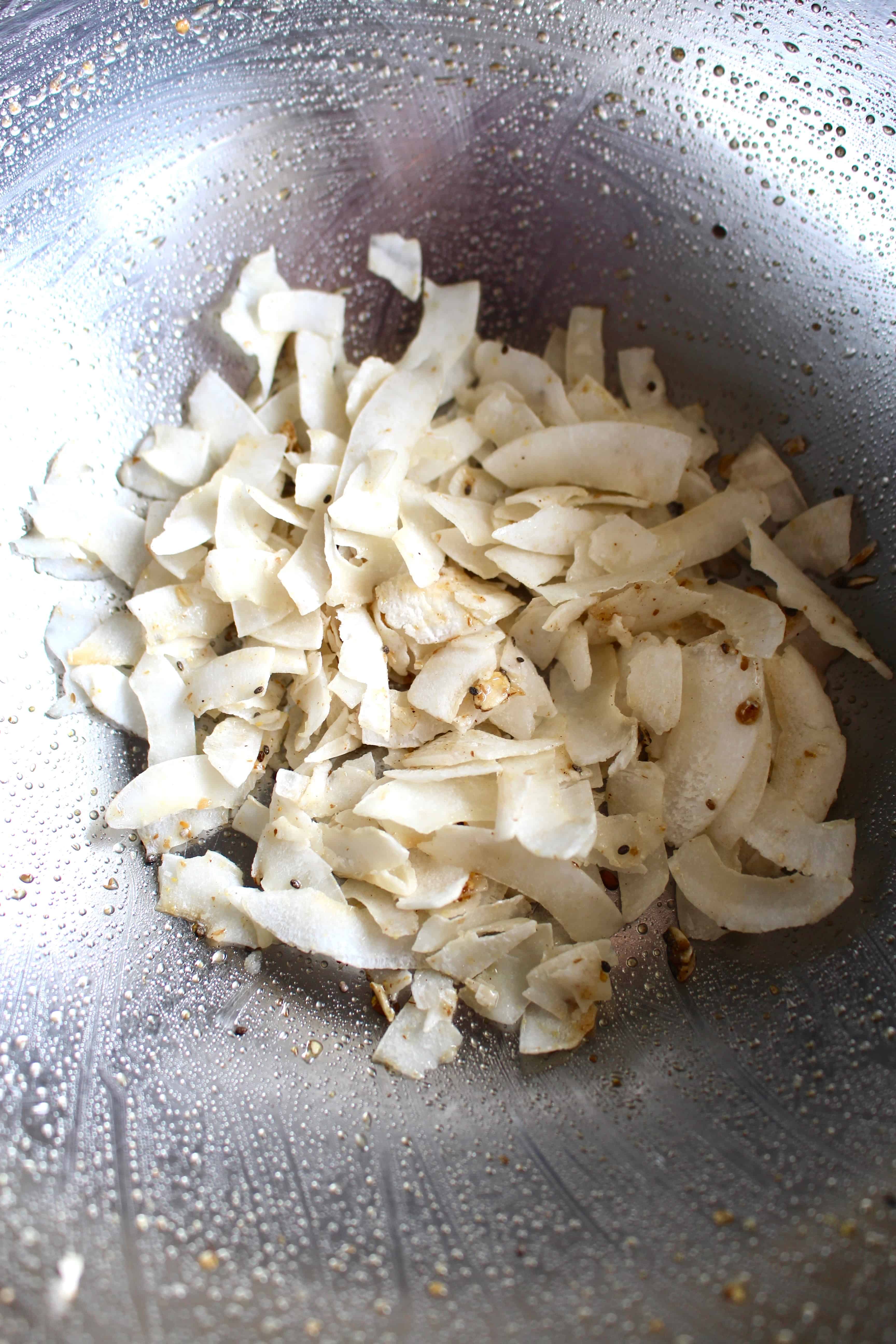 Coconut flakes tossed in a metallic bowl.