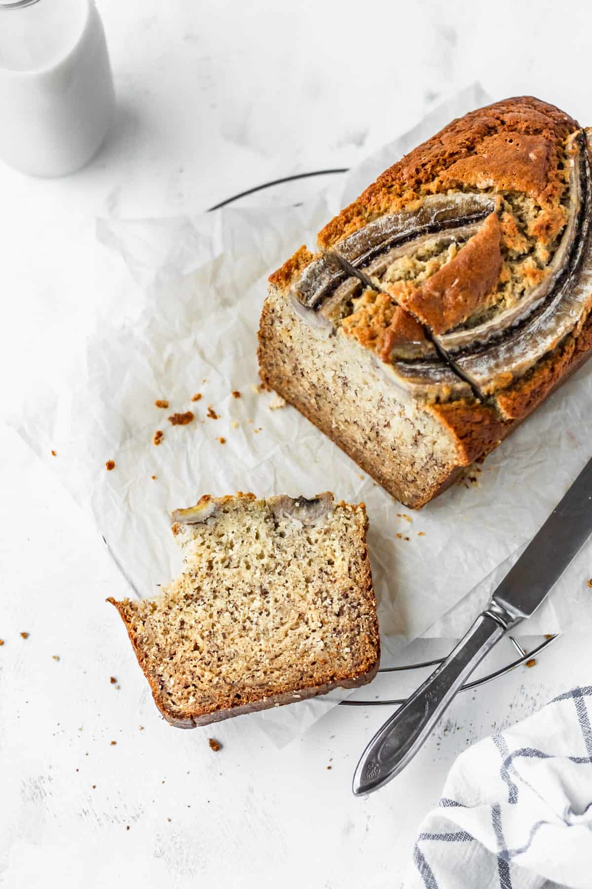 A loaf of banana bread with a bitten slice laying in front.