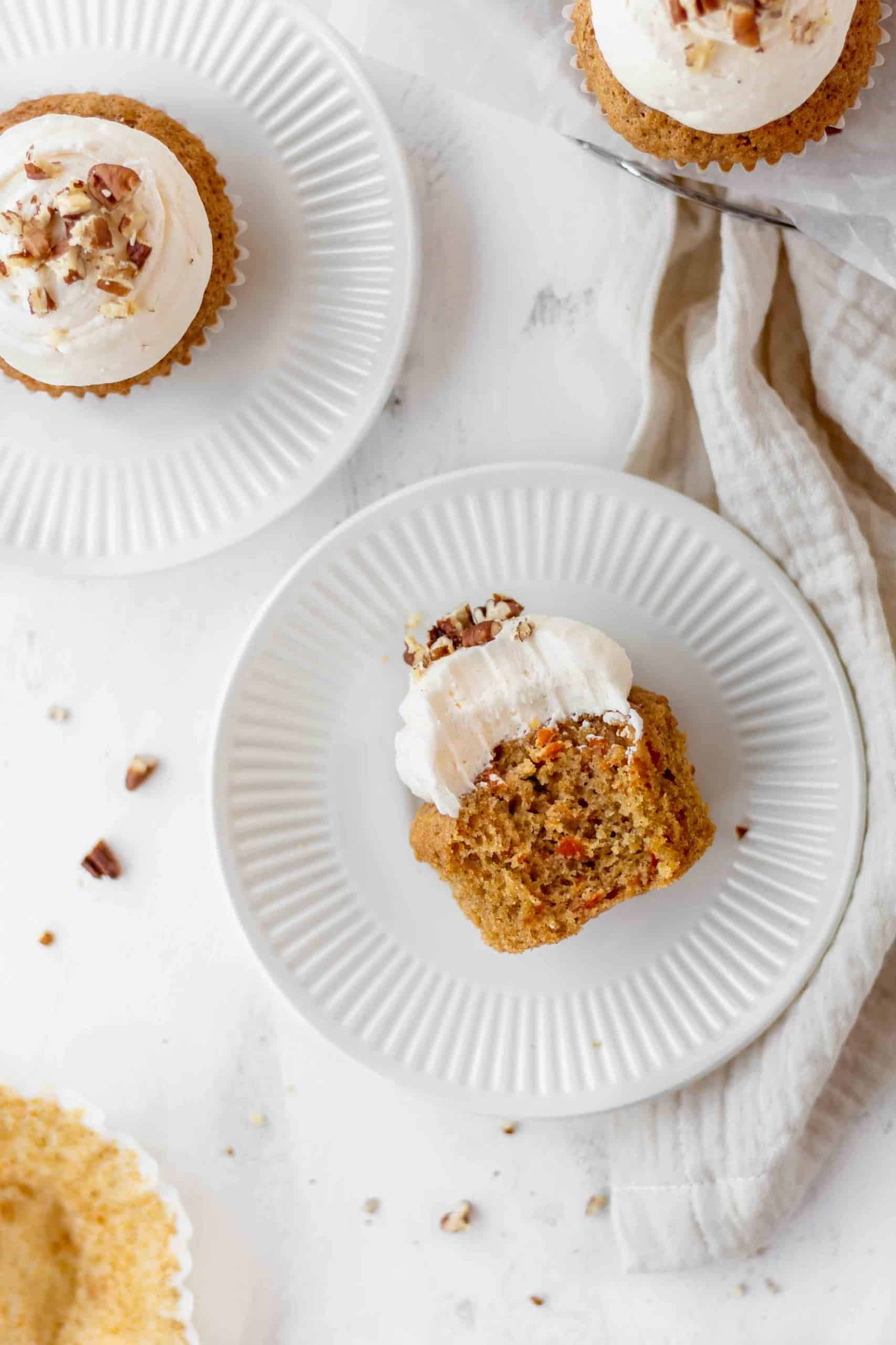 A bitten cupcake with lemon cream cheese frosting on a plate