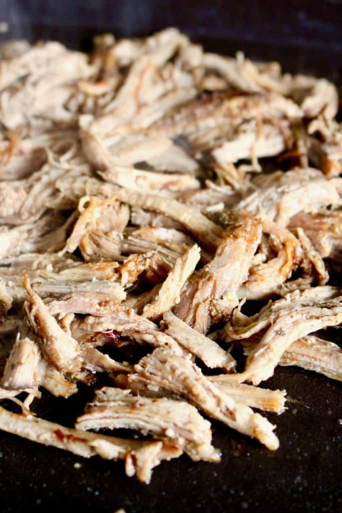 Shredded carnitas crisping up on a hot griddle.