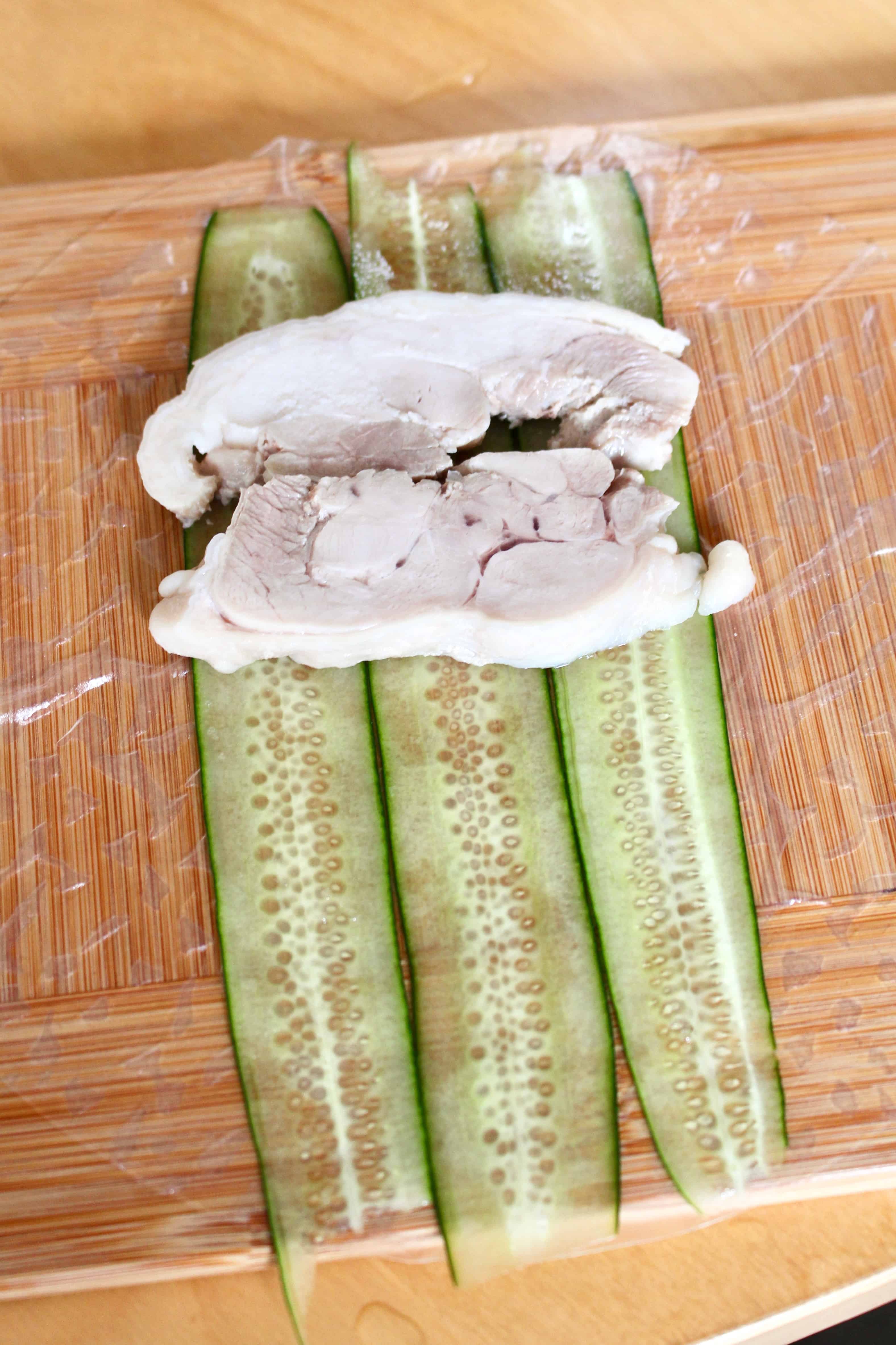 Sliced chicken thigh on sliced cucumbers.