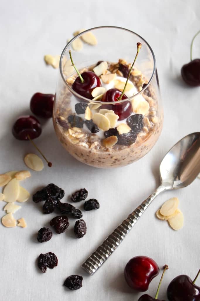 A glass of overnight oats with a silver spoon next to it.