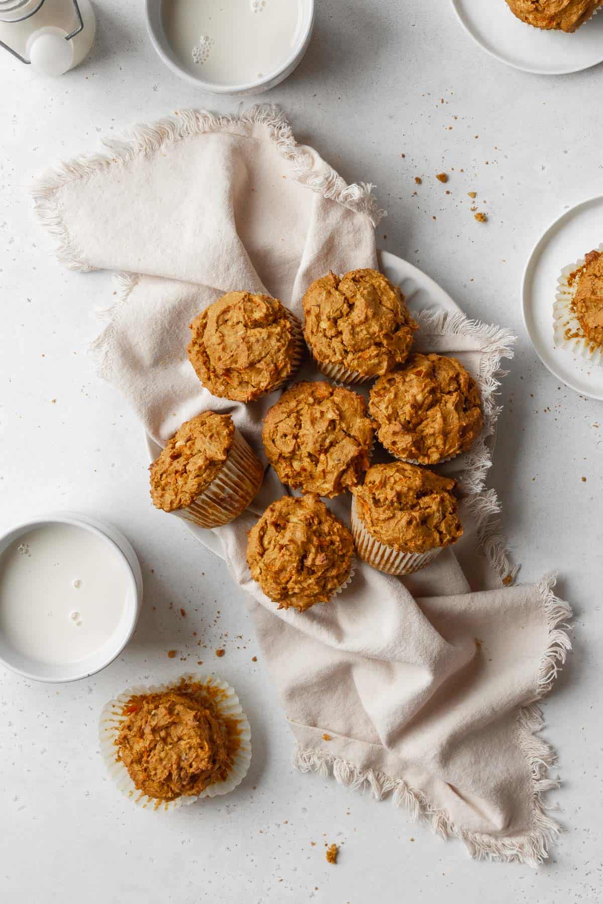 Overhead hero shot of healthy vegan morning glory muffins on a white kitchen towel on a white table.