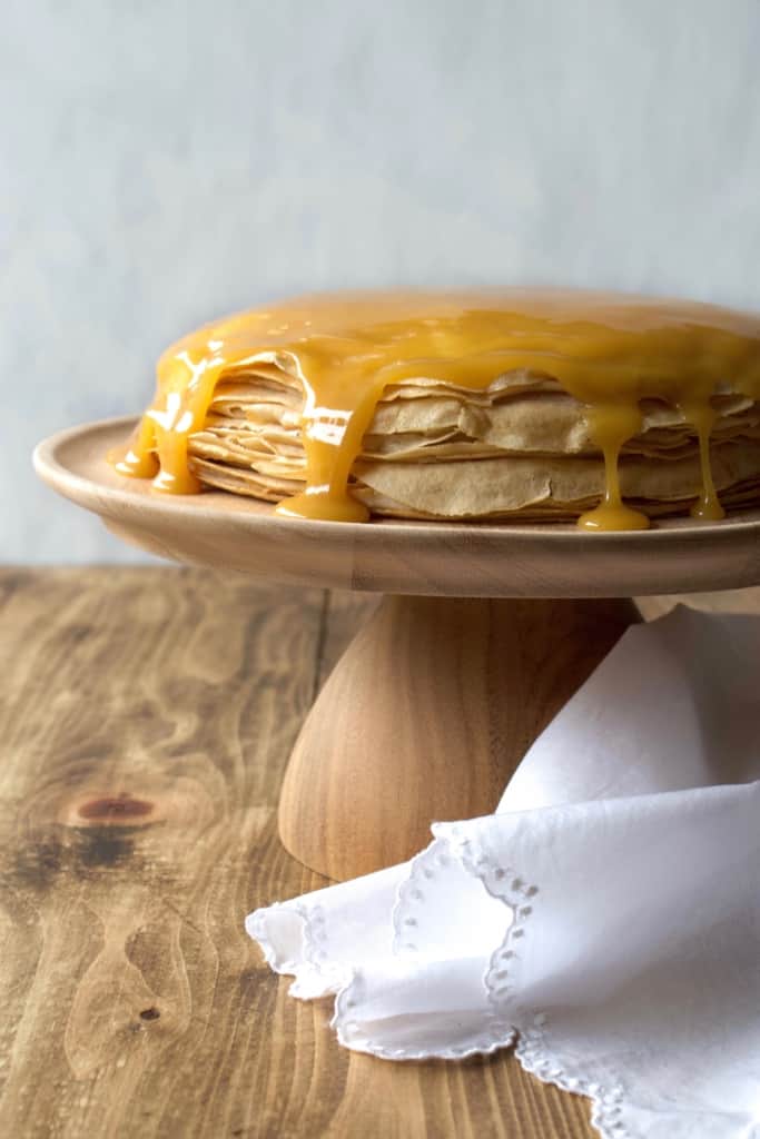 Coconut whipped cream sandwiched between layers of delicious crêpes, then topped with rich homemade dulce de leche! Whether you call it gâteau de crêpes, mille crêpe, or crepe cake, this is a beautiful and impressive dessert! #french #crepecake #crepes #pancakes #gateau #millecrepe #dulcedeleche #coconut #dairyfree #condensedmilk #caramel #cake