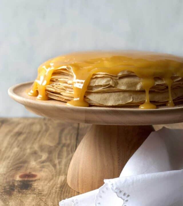 Coconut whipped cream sandwiched between layers of delicious crêpes, then topped with rich homemade dulce de leche! Whether you call it gâteau de crêpes, mille crêpe, or crepe cake, this is a beautiful and impressive dessert! #french #crepecake #crepes #pancakes #gateau #millecrepe #dulcedeleche #coconut #dairyfree #condensedmilk #caramel #cake