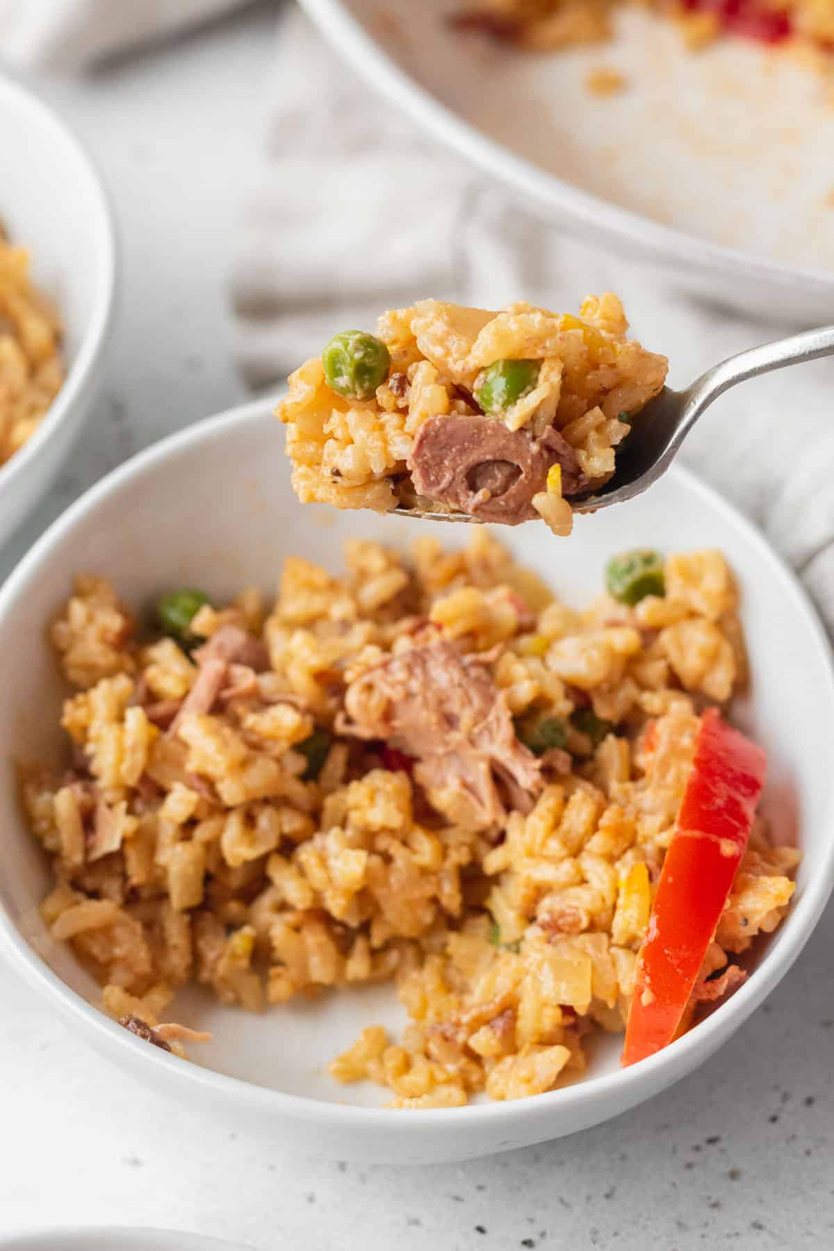 A spoonful of Filipino paella being lifted up from a bowl.