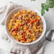 Overhead shot of vegan Arroz Valenciana in a white bowl with a spoon and natural linen.
