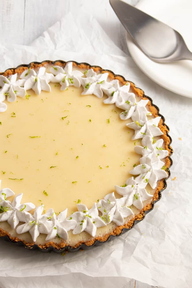 This vegan key lime pie is so creamy and tangy! With a crunchy graham cracker crust on the bottom and topped with rich coconut whipped cream, this plant based dessert won’t have you missing the traditional key lime pie! #vegandessert #vegankeylimepie #keylimepie #nobakedessert #nobakepie #plantbaseddessert