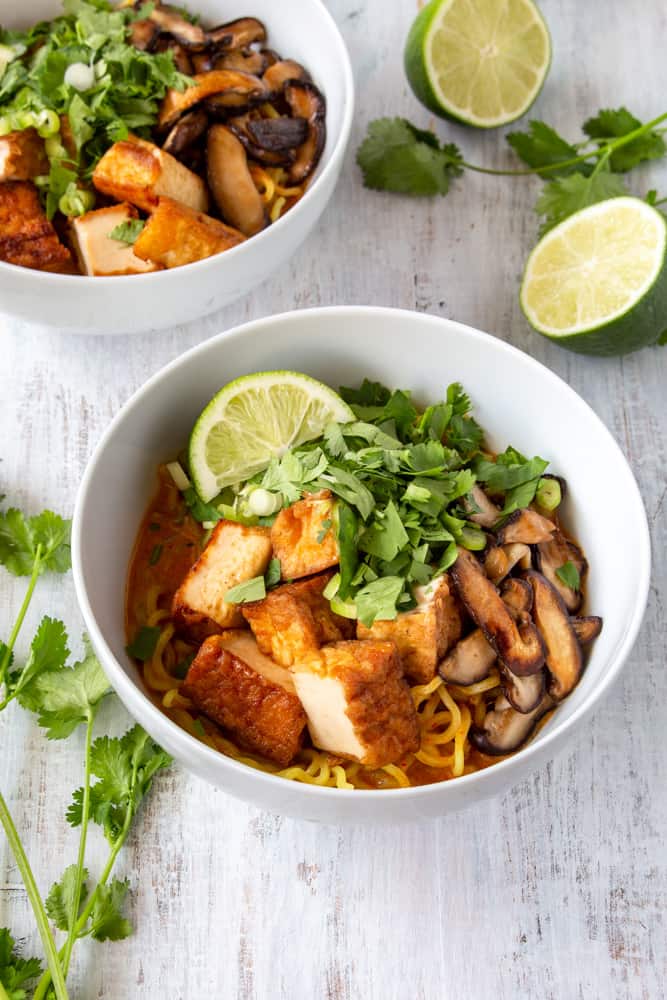 This vegan Thai red curry ramen is your new go-to quick and easy comfort food! Red curry paste and coconut milk make the perfect spicy and creamy soup for ramen noodles, deep fried tofu, and sautéed shiitake mushrooms. The scallions, cilantro, and lime juice tie it all together in this vegan fusion deliciousness! #veganrecipe #veganramen #thairedcurry #currypaste #coconutmilk