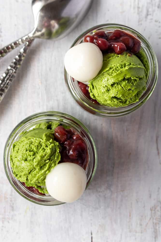 Two jars with matcha ice cream, shiratama, and red bean paste.