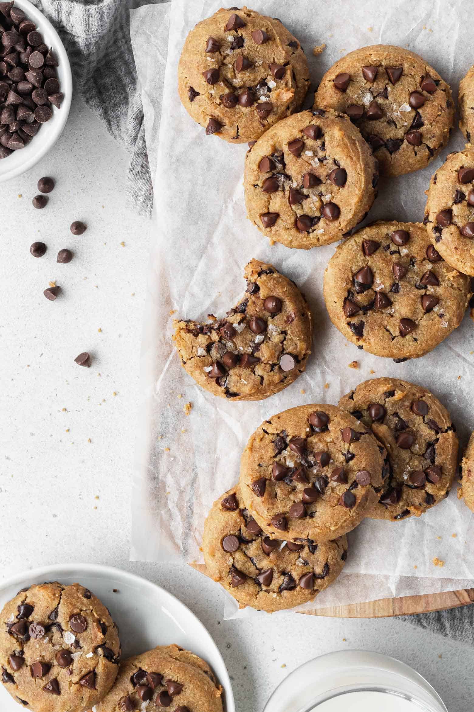 Chocolate chip chickpea cookies scattered on a parchment paper.