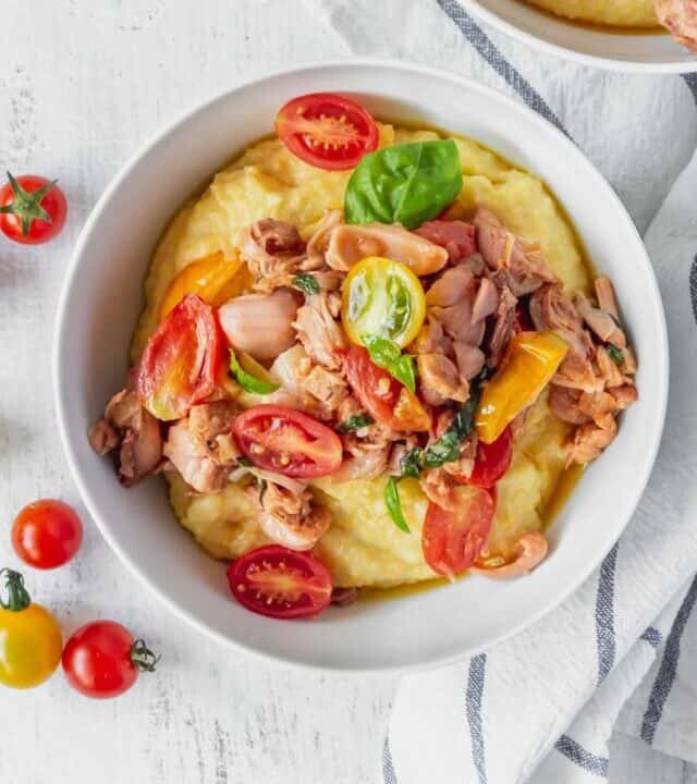 This vegan grits recipe is the perfect gluten-free meal! Creamy vegan polenta cooked in coconut milk is topped with savory jackfruit confit with tomatoes and basil!