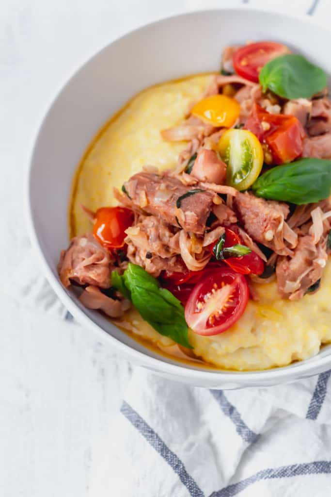 This vegan grits recipe is the perfect gluten-free meal! Creamy vegan polenta cooked in coconut milk is topped with savory jackfruit confit with tomatoes and basil!