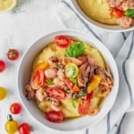 This vegan grits recipe is the perfect gluten-free meal! Creamy vegan polenta cooked in coconut milk is topped with savory jackfruit confit with tomatoes and basil!