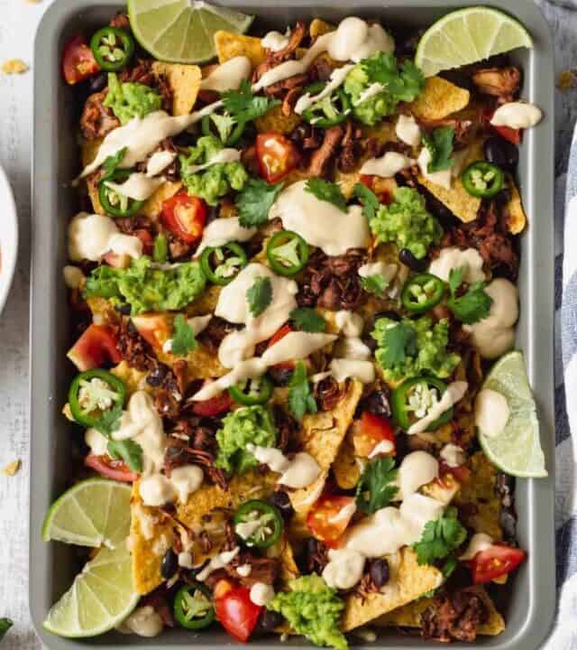Vegan nachos with jackfruit and vegan queso is amazing! Tortilla chips, jackfruit, black beans, tomatoes, guacamole, jalapeños, cilantro, and creamy queso! #vegannachos #vegancheese #veganqueso #jackfruit #veganmexicanfood