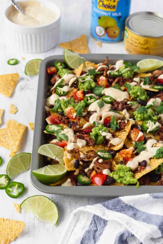Vegan nachos with jackfruit and vegan queso is amazing! Tortilla chips, jackfruit, black beans, tomatoes, guacamole, jalapeños, cilantro, and creamy queso! #vegannachos #vegancheese #veganqueso #jackfruit #veganmexicanfood