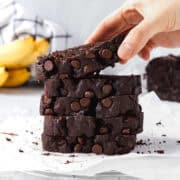 A slice of chocolate banana bread being picked up by a hand.
