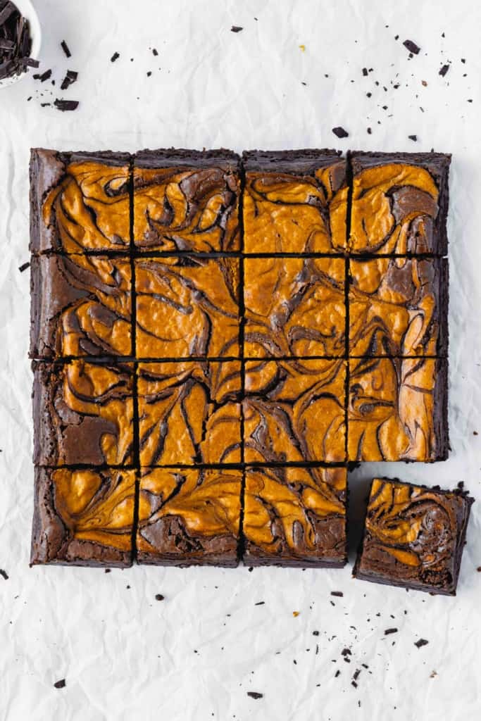Pumpkin cheesecake brownies cut into squares on parchment paper.