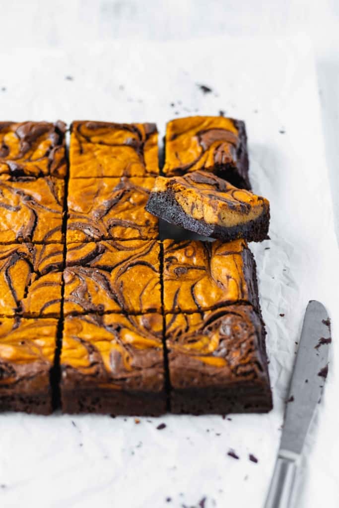 A square of pumpkin cheesecake brownie lifted up from the rest of the squares.