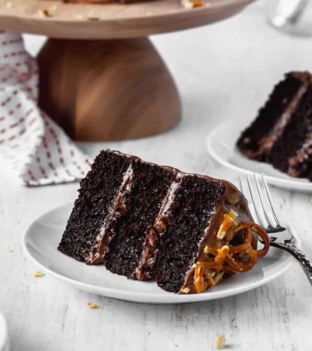 A slice of moist and fluffy chocolate cake with peanuts, pretzels, and chocolate buttercream frosting