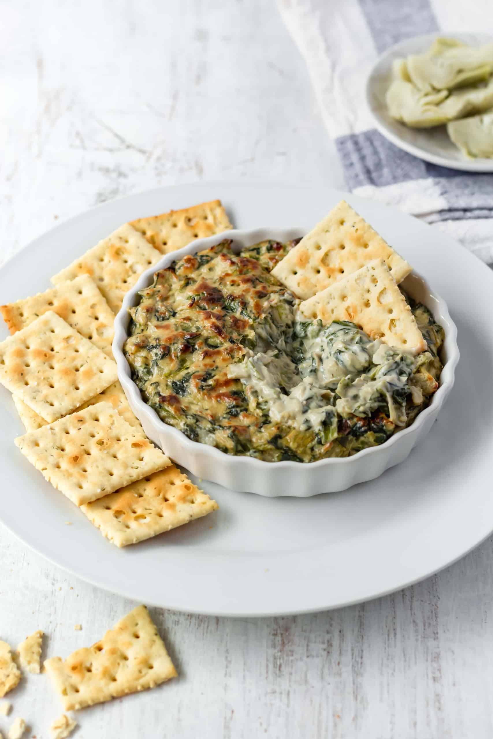 Two cracker in a dish of vegan spinach dip.