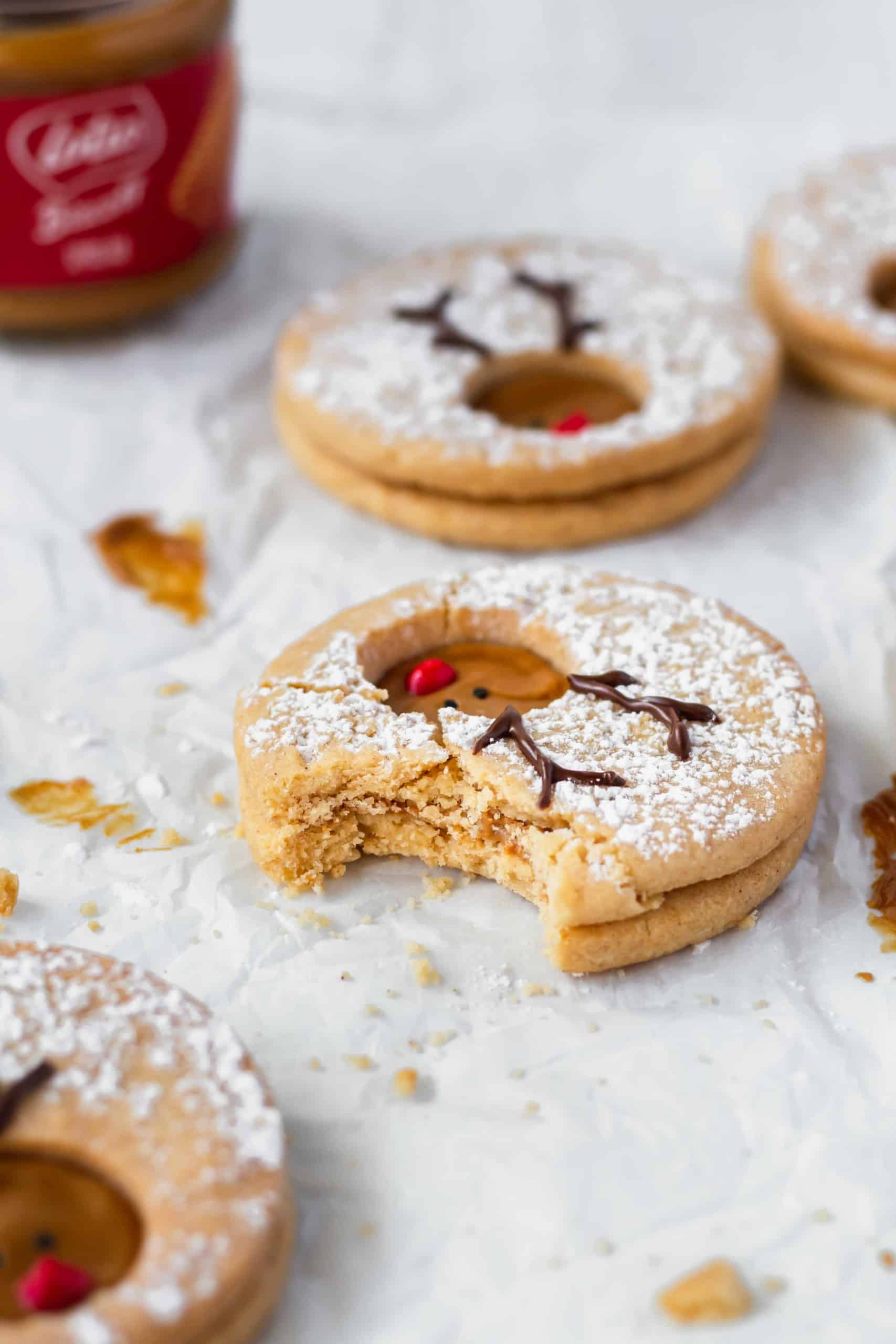 A bitten reindeer cookie on a white surface.