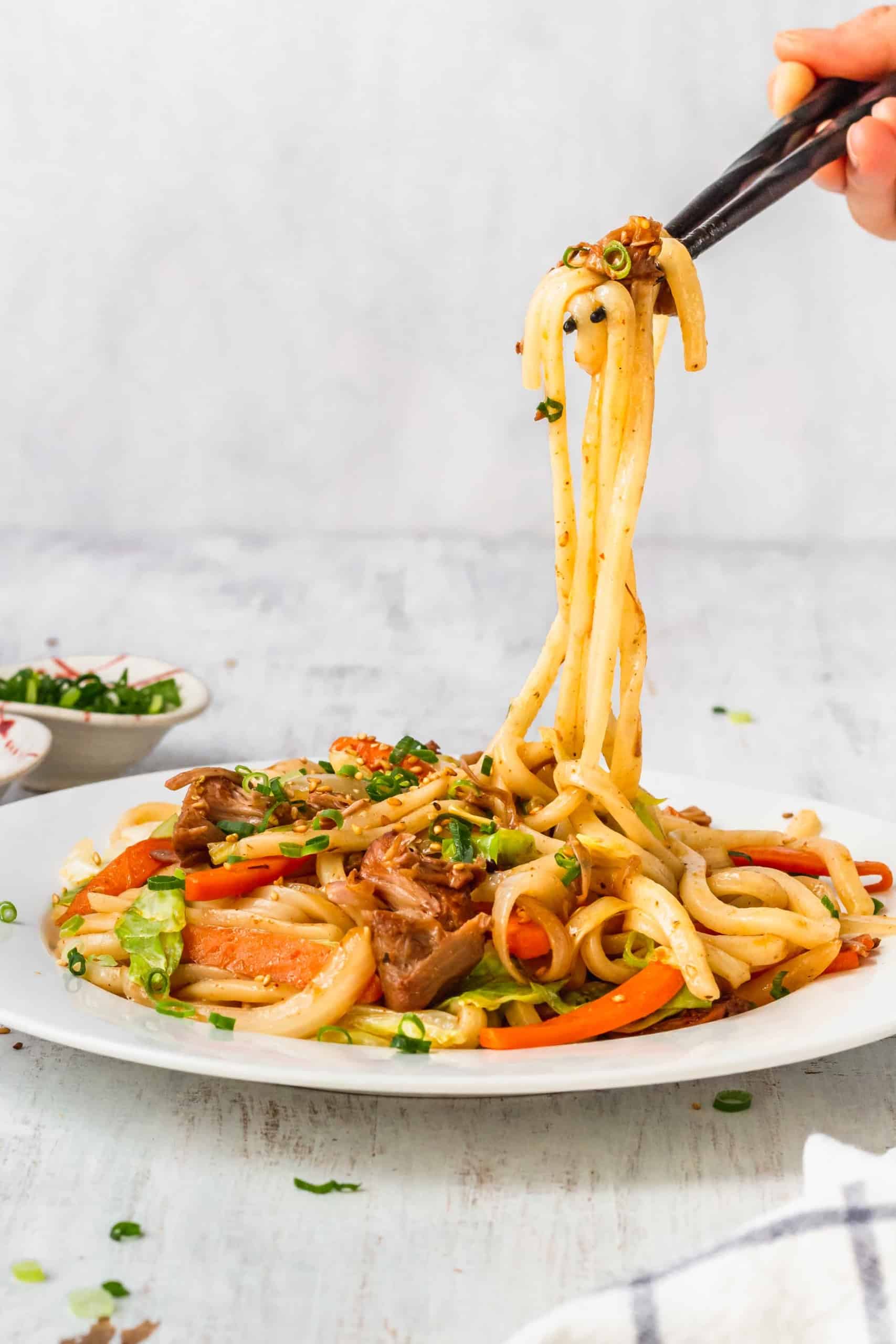 Vegan massaman noodles being lifted with chopsticks