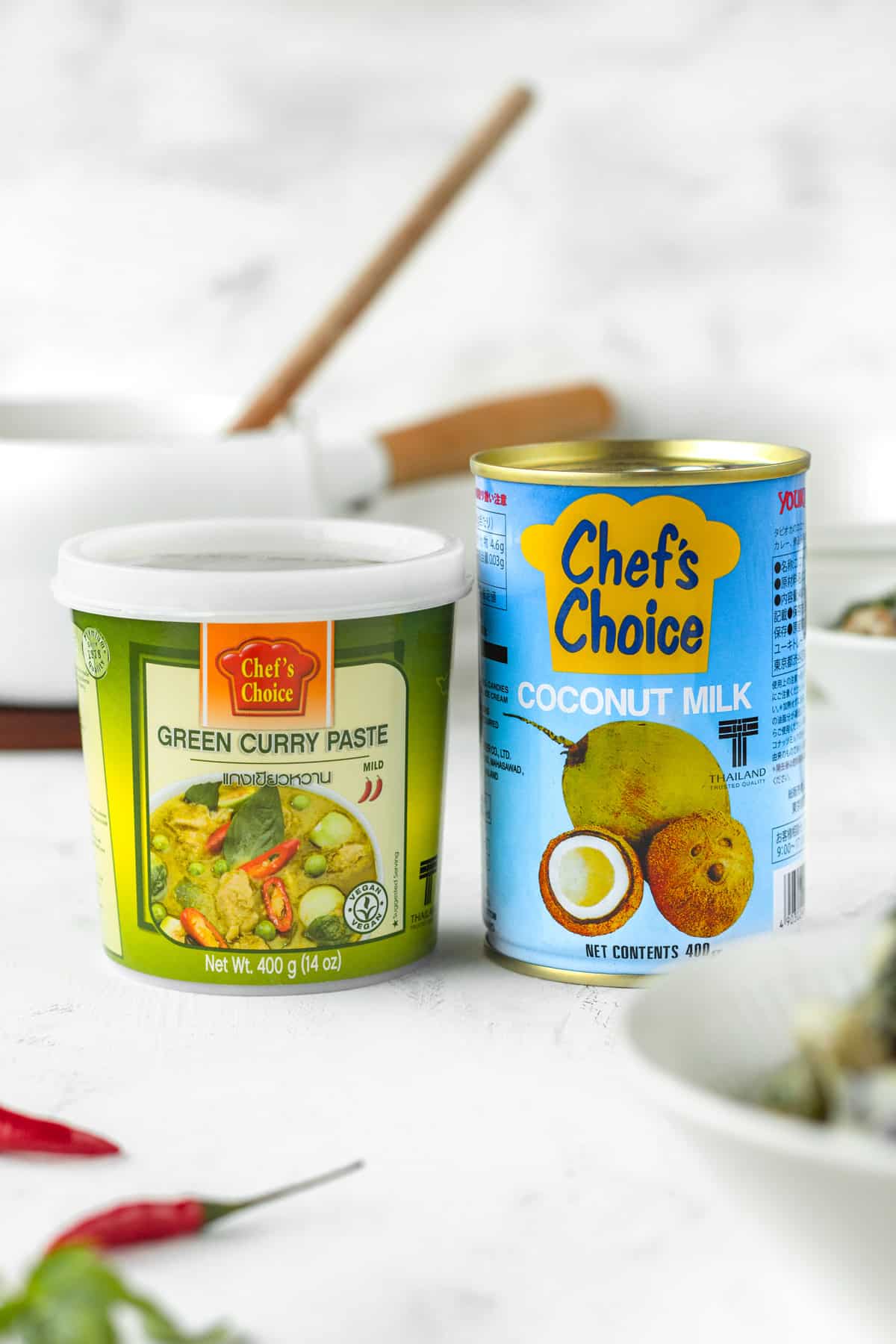 A can of coconut milk next to a container of green curry paste.