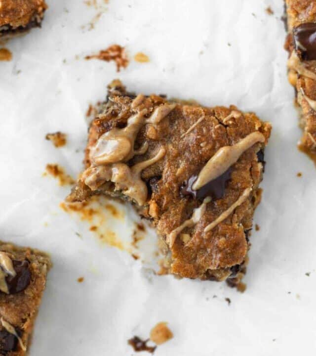 A bite taken out of an oatmeal bar with peanut butter drizzled on top