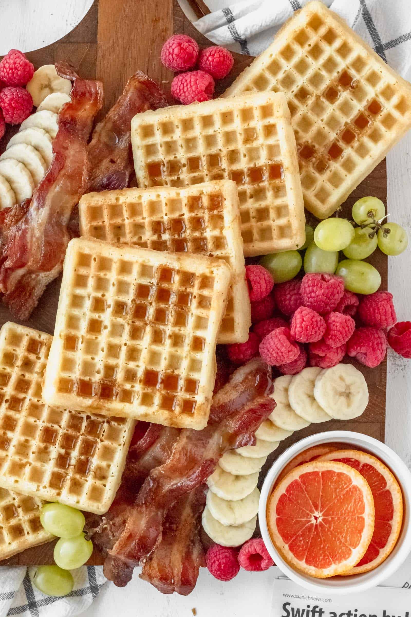 Waffles on a breakfast charcuterie board drizzled with maple syrup