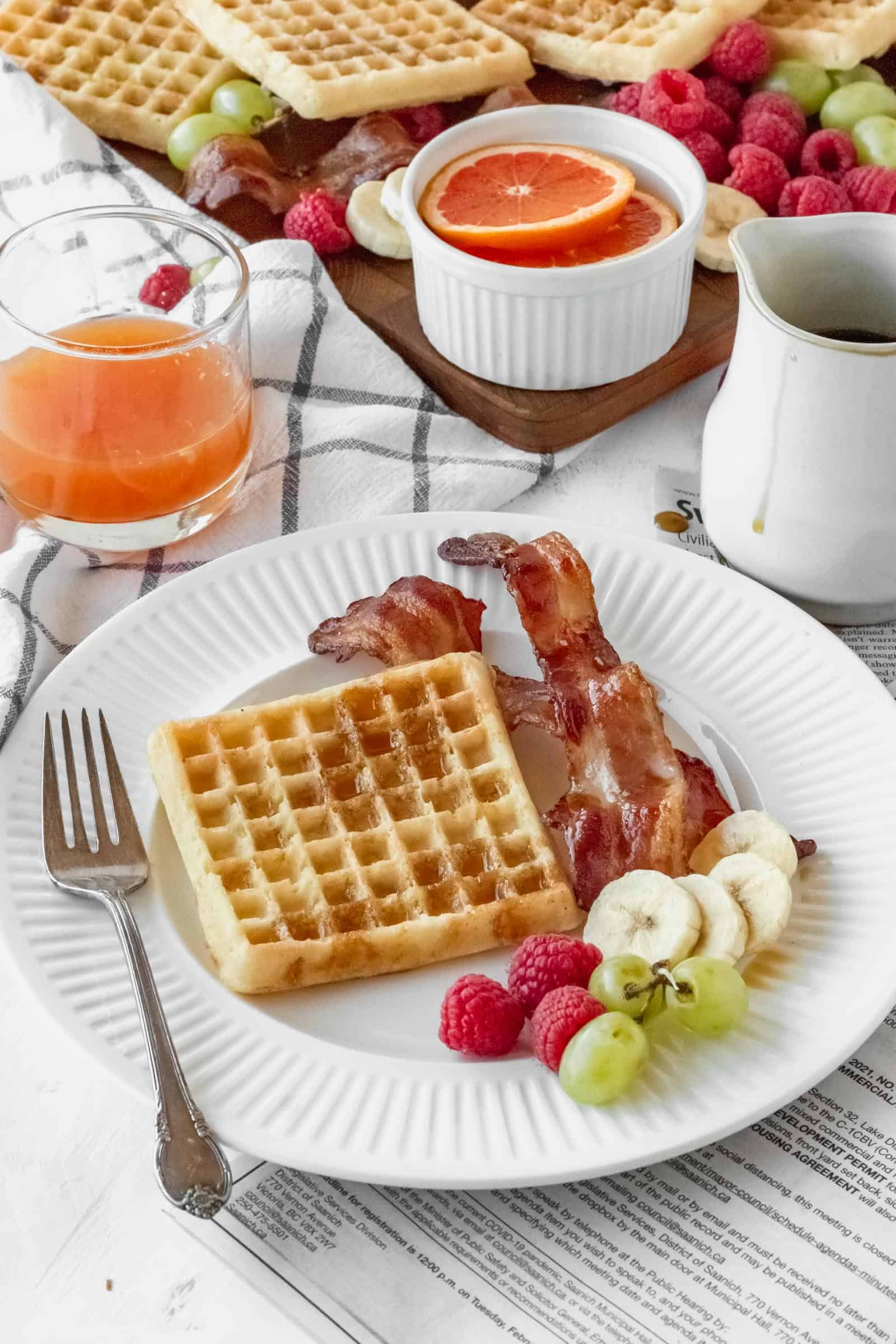 Waffle, bacon, and fruit on a plate at breakfast