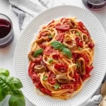 Plate of spaghetti with roasted tomatoes and vegan calamari with two glasses of red wine