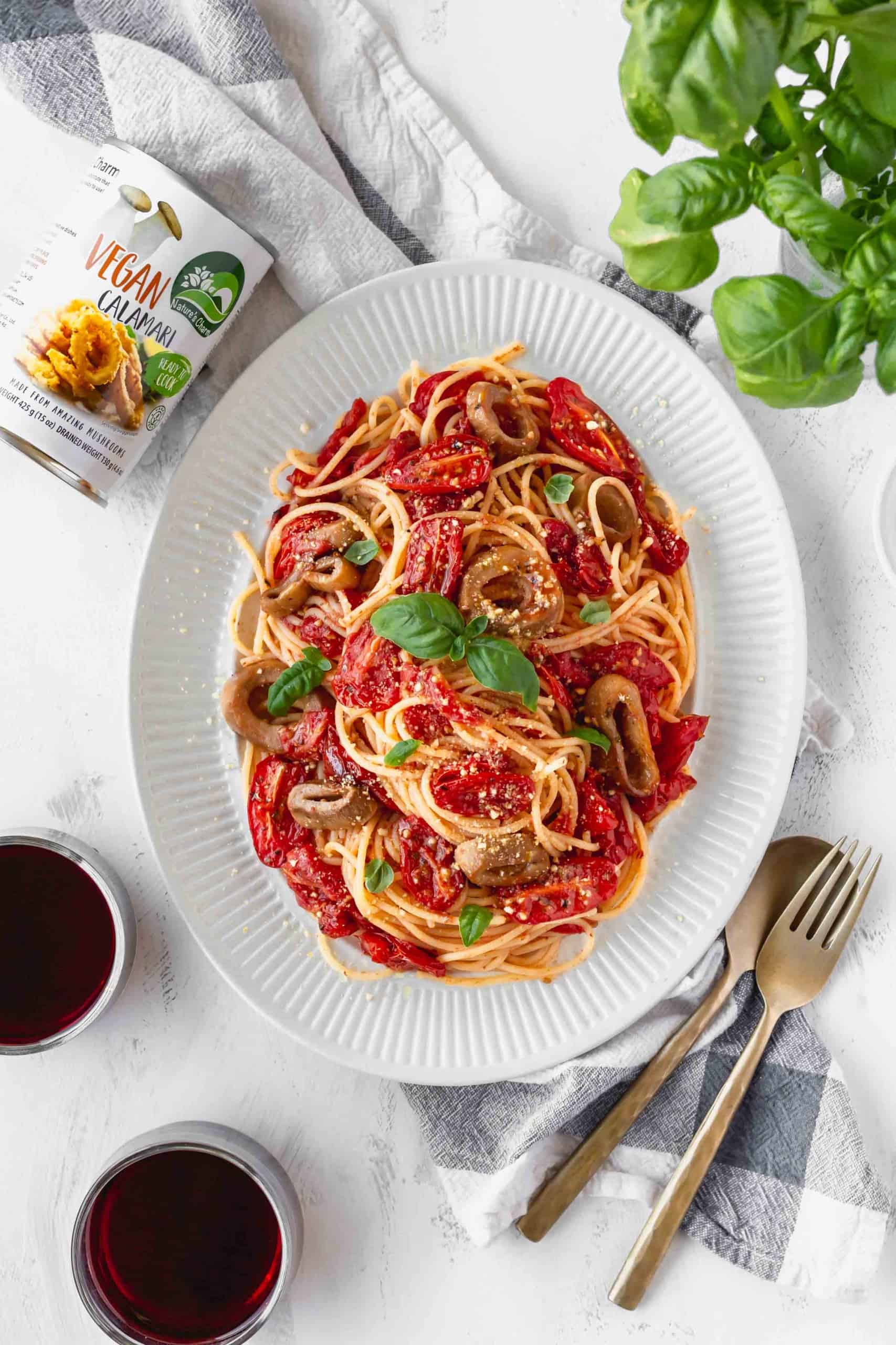 A plate of vegan and gluten-free spaghetti with cherry tomato sauce and a can of vegan calamari