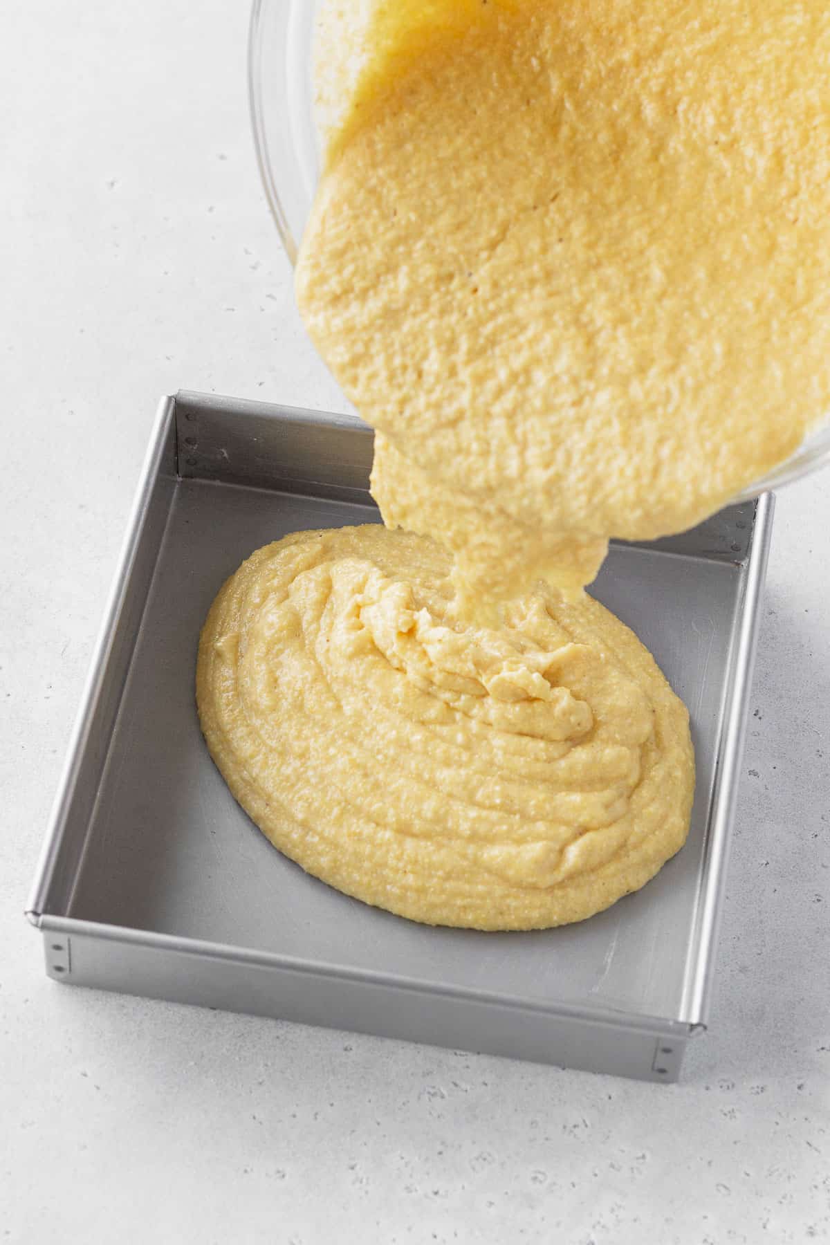 Pouring cornbread batter into prepared baking tin.