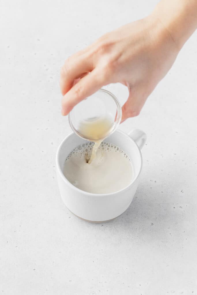 Pouring ACV into non-dairy milk to make vegan buttermilk.